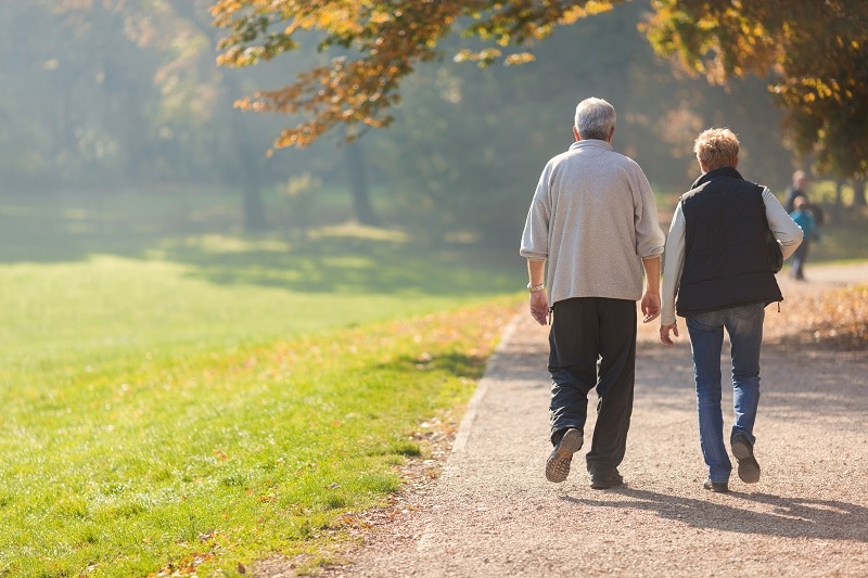 senior citizen couple taking a walk in a park during autumn morning | retirement community cleaning