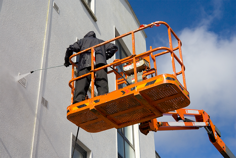 man pressure washing exterior walls of a building | pressure wash large buildings